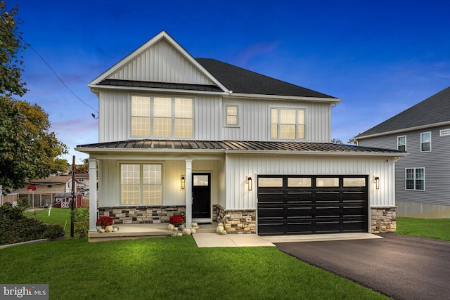 view of front of house with a porch, a garage, and a lawn