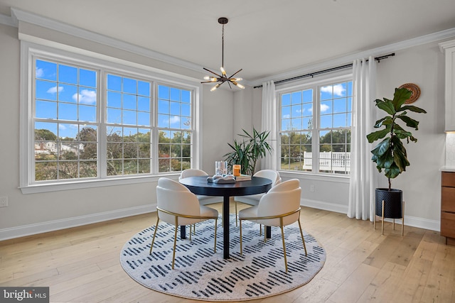 dining room with a notable chandelier, ornamental molding, and light hardwood / wood-style flooring