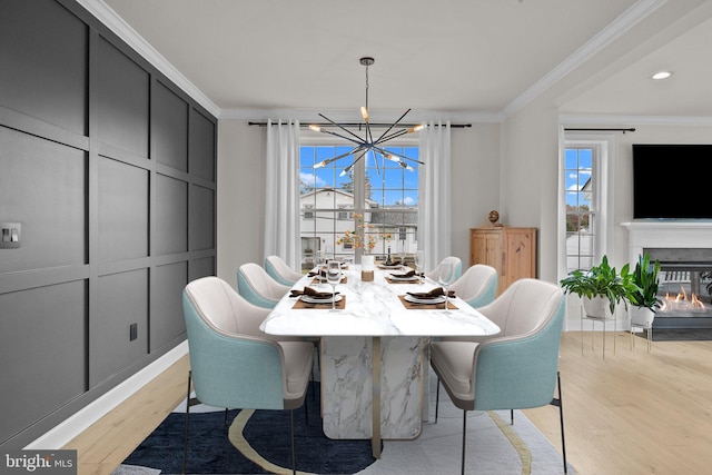 dining area with ornamental molding, a chandelier, and light wood-type flooring