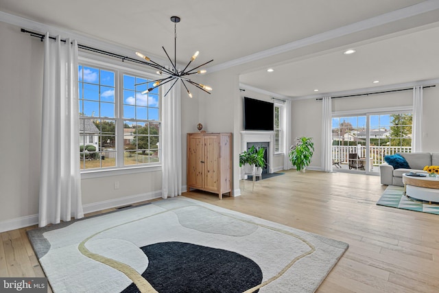 living area featuring crown molding, a notable chandelier, and light wood-type flooring