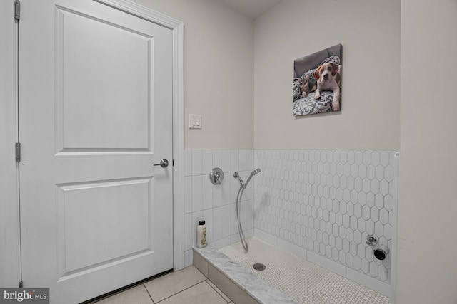 bathroom with a tile shower, tile patterned floors, and tile walls