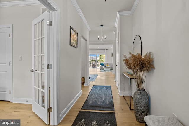 interior space with light hardwood / wood-style floors, an inviting chandelier, ornamental molding, and french doors