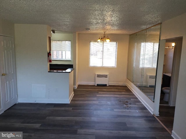 unfurnished dining area with a textured ceiling, plenty of natural light, dark hardwood / wood-style flooring, and radiator heating unit