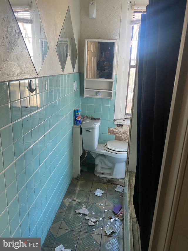 bathroom featuring tile walls, tile patterned floors, and toilet