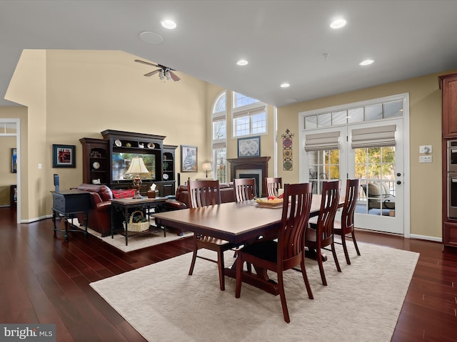 dining space with dark hardwood / wood-style flooring, ceiling fan, and a high ceiling