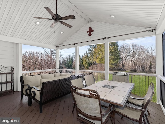 sunroom / solarium with ceiling fan, plenty of natural light, and vaulted ceiling