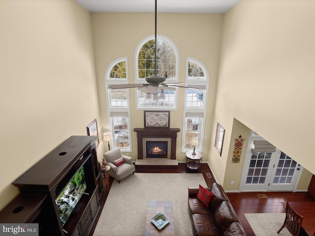 living room featuring a towering ceiling, ceiling fan, and hardwood / wood-style flooring