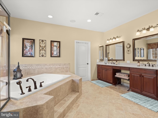 bathroom with tile patterned flooring, vanity, and a relaxing tiled tub