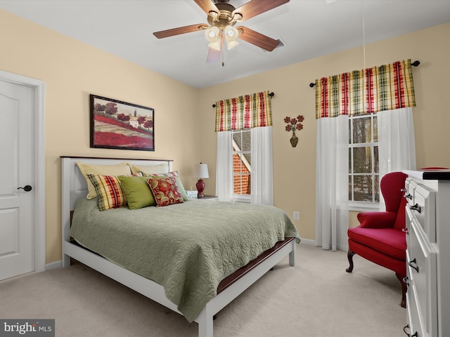 bedroom with light carpet, multiple windows, and ceiling fan