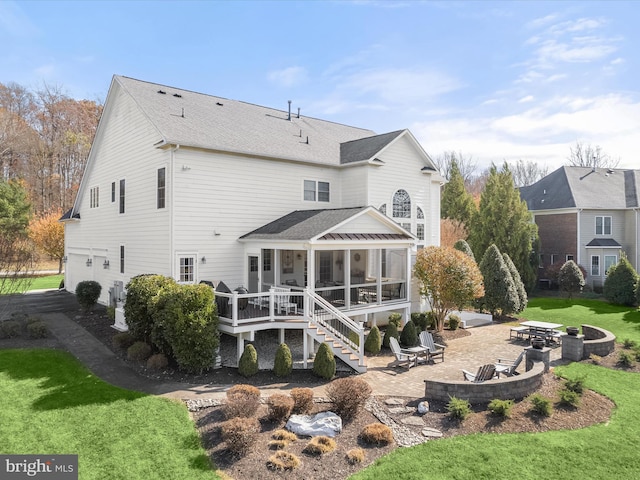 back of house featuring a patio, a wooden deck, a yard, an outdoor fire pit, and a sunroom