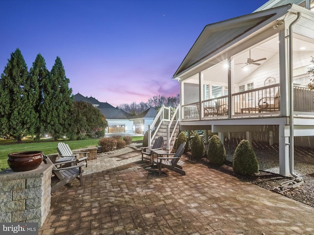 patio terrace at dusk with ceiling fan and an outdoor fire pit