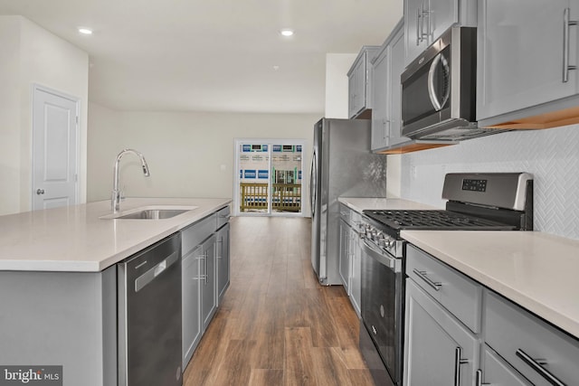 kitchen featuring tasteful backsplash, sink, dark hardwood / wood-style flooring, stainless steel appliances, and a center island with sink