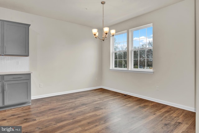 unfurnished dining area with an inviting chandelier and dark hardwood / wood-style floors