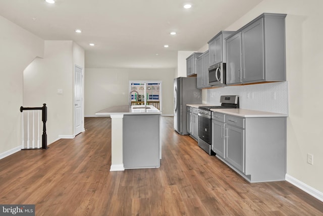 kitchen with appliances with stainless steel finishes, sink, a center island with sink, and gray cabinetry