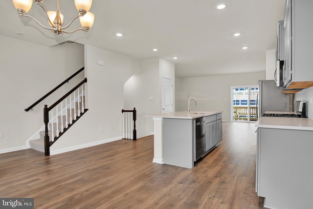 kitchen with gray cabinetry, stainless steel appliances, dark hardwood / wood-style floors, an island with sink, and decorative light fixtures