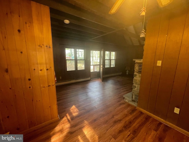 spare room with a stone fireplace, wooden walls, and dark wood-type flooring