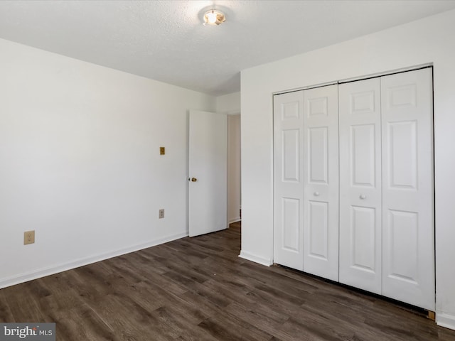 unfurnished bedroom featuring dark wood-type flooring, a textured ceiling, and a closet