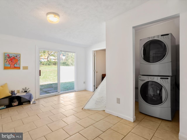 laundry room with a textured ceiling, stacked washer / drying machine, and light tile patterned floors