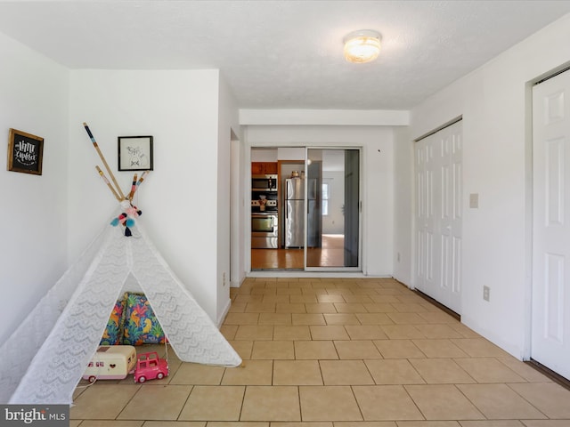 rec room with a textured ceiling and light tile patterned floors