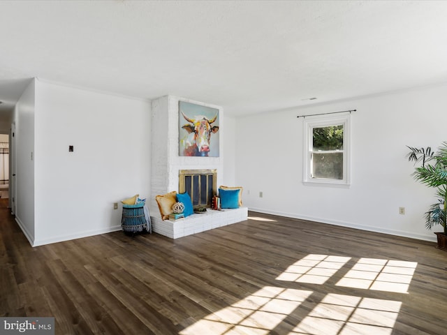 unfurnished room featuring a brick fireplace and dark hardwood / wood-style flooring