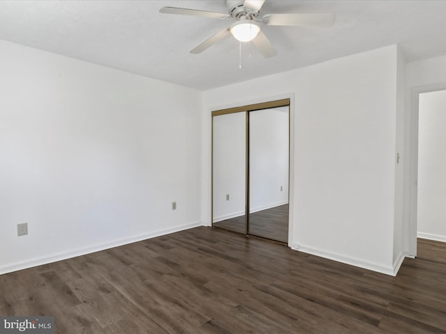 unfurnished bedroom featuring a closet, dark wood-type flooring, and ceiling fan