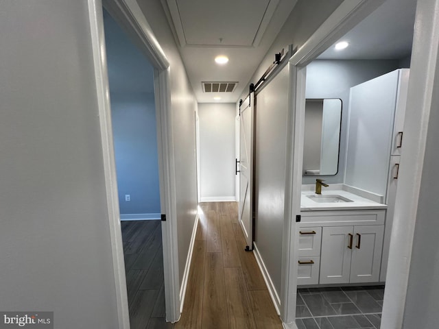 hall featuring a barn door, dark hardwood / wood-style floors, and sink