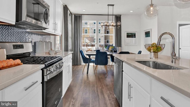 kitchen featuring sink, dark hardwood / wood-style flooring, white cabinetry, stainless steel appliances, and decorative light fixtures