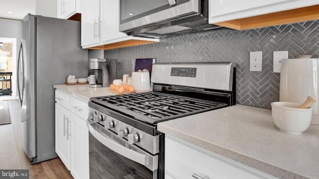 kitchen featuring backsplash, appliances with stainless steel finishes, white cabinetry, and light wood-type flooring