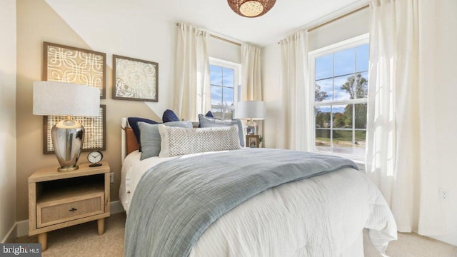 carpeted bedroom with vaulted ceiling and multiple windows