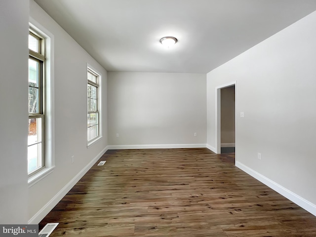 spare room featuring visible vents, baseboards, and wood finished floors