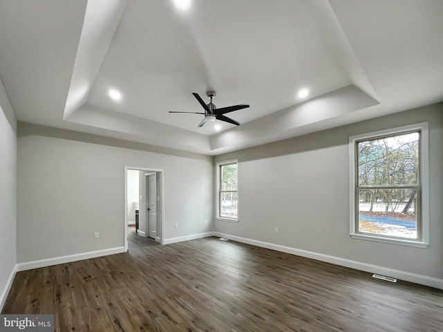 unfurnished bedroom featuring dark wood-type flooring, baseboards, and a raised ceiling