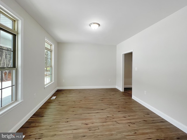 spare room featuring visible vents, baseboards, and wood finished floors