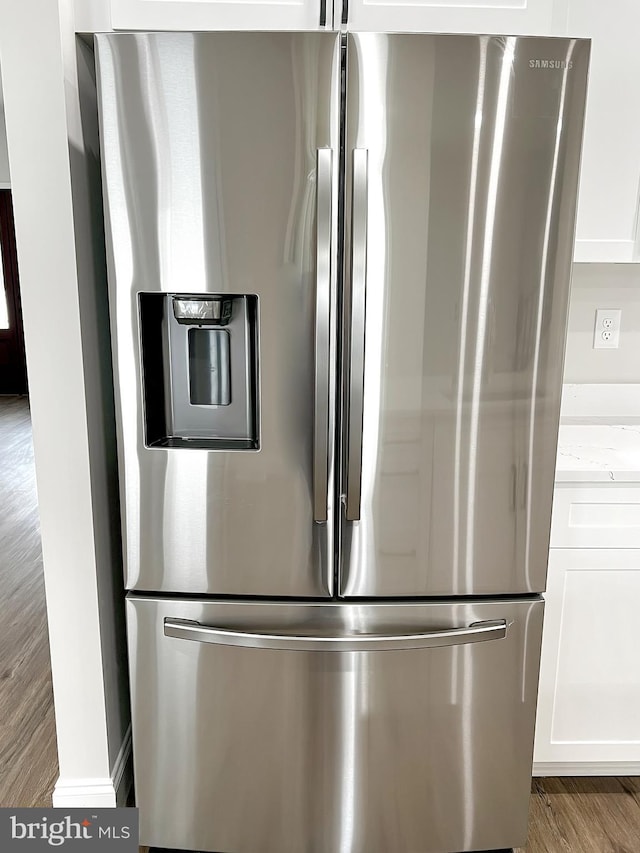 room details featuring wood finished floors, white cabinetry, light stone countertops, and stainless steel refrigerator with ice dispenser