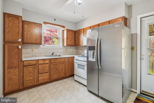 kitchen featuring white range, sink, decorative backsplash, stainless steel fridge, and ceiling fan