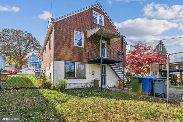 rear view of property featuring a lawn and a balcony