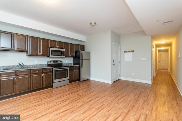 kitchen featuring dark brown cabinetry, stainless steel appliances, sink, and light hardwood / wood-style flooring