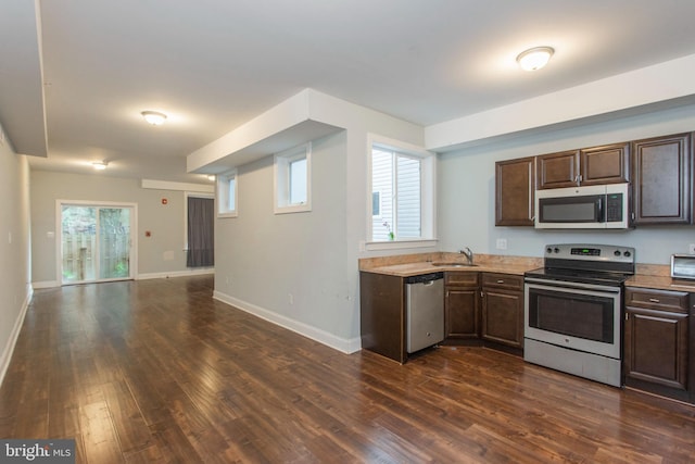 kitchen featuring dark brown cabinetry, appliances with stainless steel finishes, dark wood-type flooring, and a healthy amount of sunlight