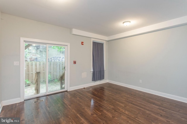 spare room featuring visible vents, baseboards, and wood finished floors