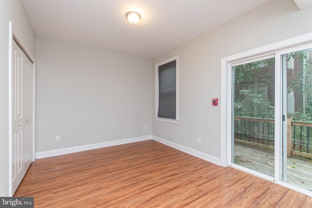 unfurnished bedroom featuring a closet, access to outside, and light hardwood / wood-style flooring