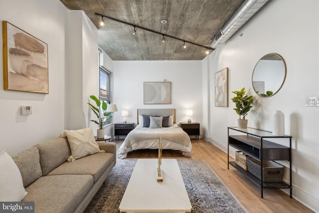 bedroom with rail lighting and light hardwood / wood-style floors