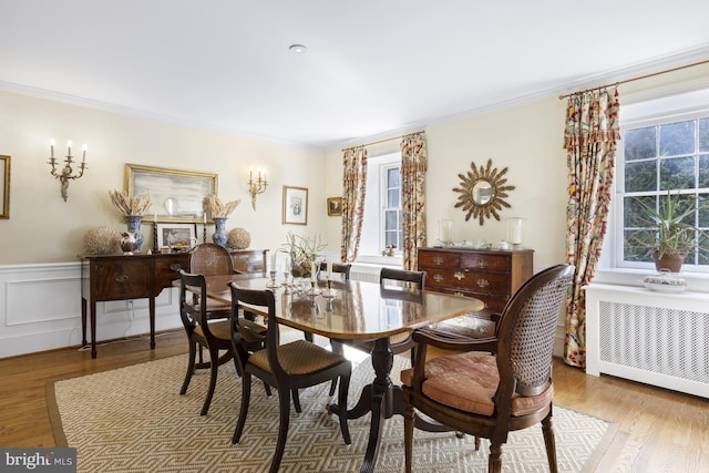 dining area with light hardwood / wood-style floors, ornamental molding, and radiator heating unit