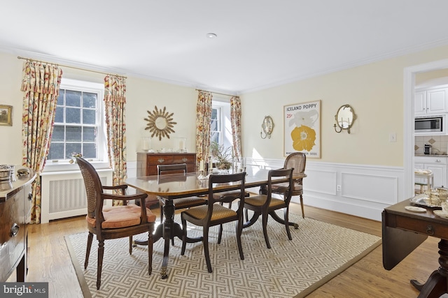 dining area featuring radiator, crown molding, and light hardwood / wood-style flooring