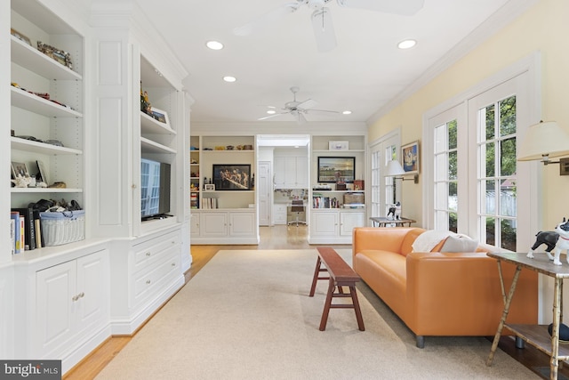 living room featuring light hardwood / wood-style floors, ornamental molding, ceiling fan, and built in shelves