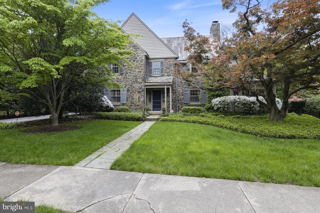 view of front of property with a chimney, stone siding, and a front yard