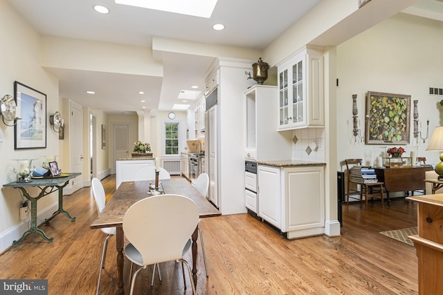 dining area with recessed lighting, visible vents, light wood-style floors, a skylight, and a baseboard radiator