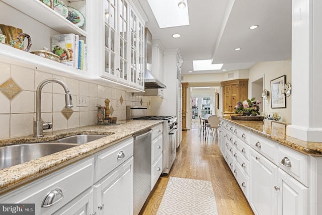 kitchen with light stone countertops, sink, light hardwood / wood-style floors, stainless steel appliances, and white cabinets