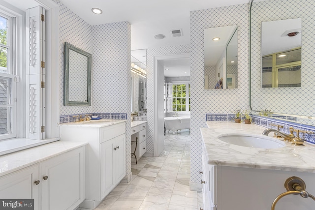 bathroom featuring a freestanding bath, visible vents, marble finish floor, and a sink