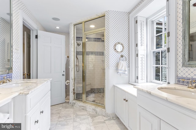 bathroom featuring recessed lighting, a shower stall, marble finish floor, a sink, and two vanities