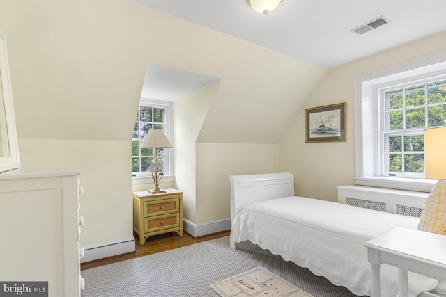 bedroom featuring visible vents, radiator heating unit, lofted ceiling, baseboard heating, and wood finished floors