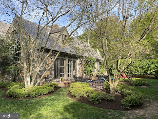 back of property with a patio area and stone siding